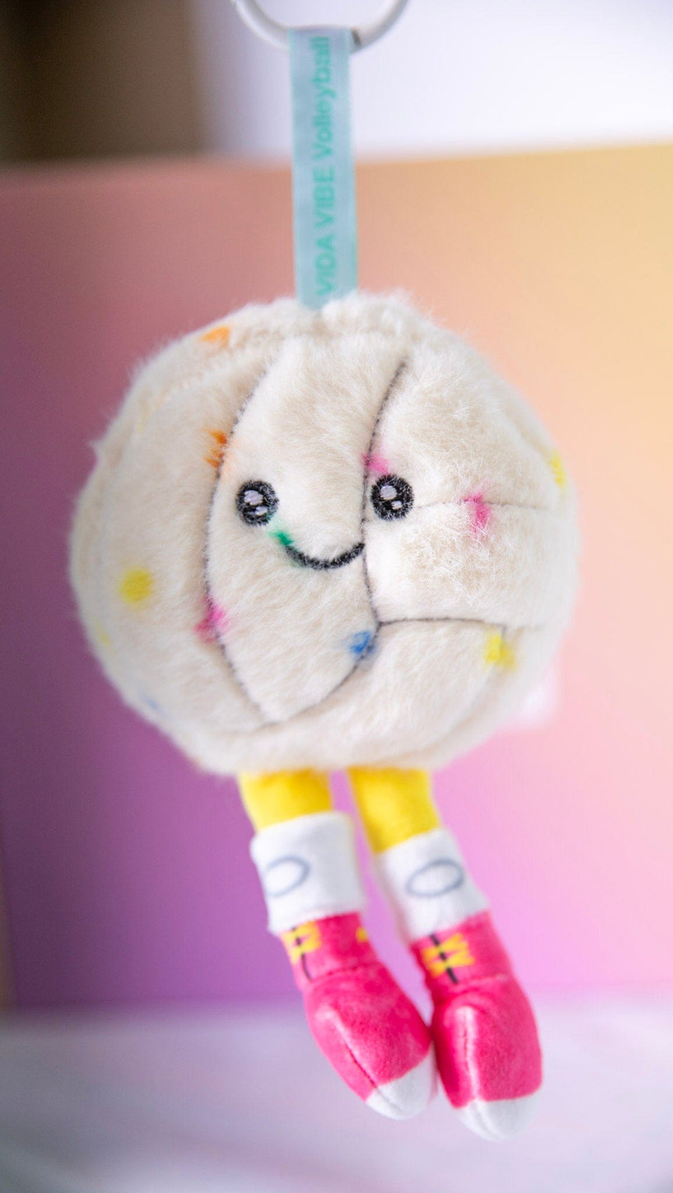 Plush toy with a smiley volleyball face on a pastel background